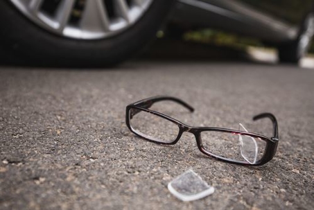 broken pair of glasses on the road next to a car