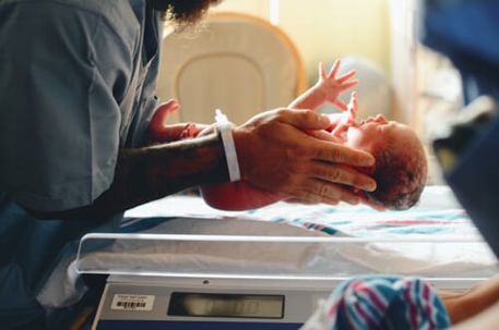 A hospital nurse places a newborn infant in its crib.