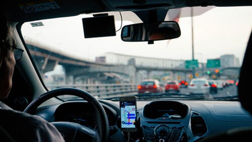 A driver uses his phone to navigate on the highway with traffic ahead.