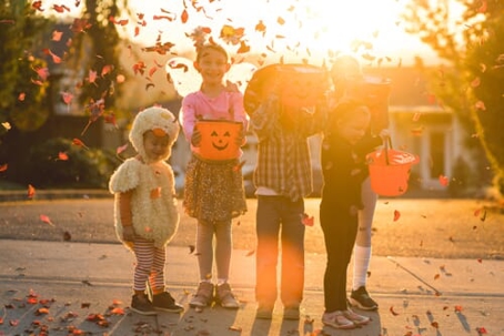 A cropped shot of trick-or-treater facing away with pumpkin candy basket in hand.