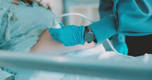 A OB/GYN conducts an ultrasound on pregnant woman to assess baby's health.